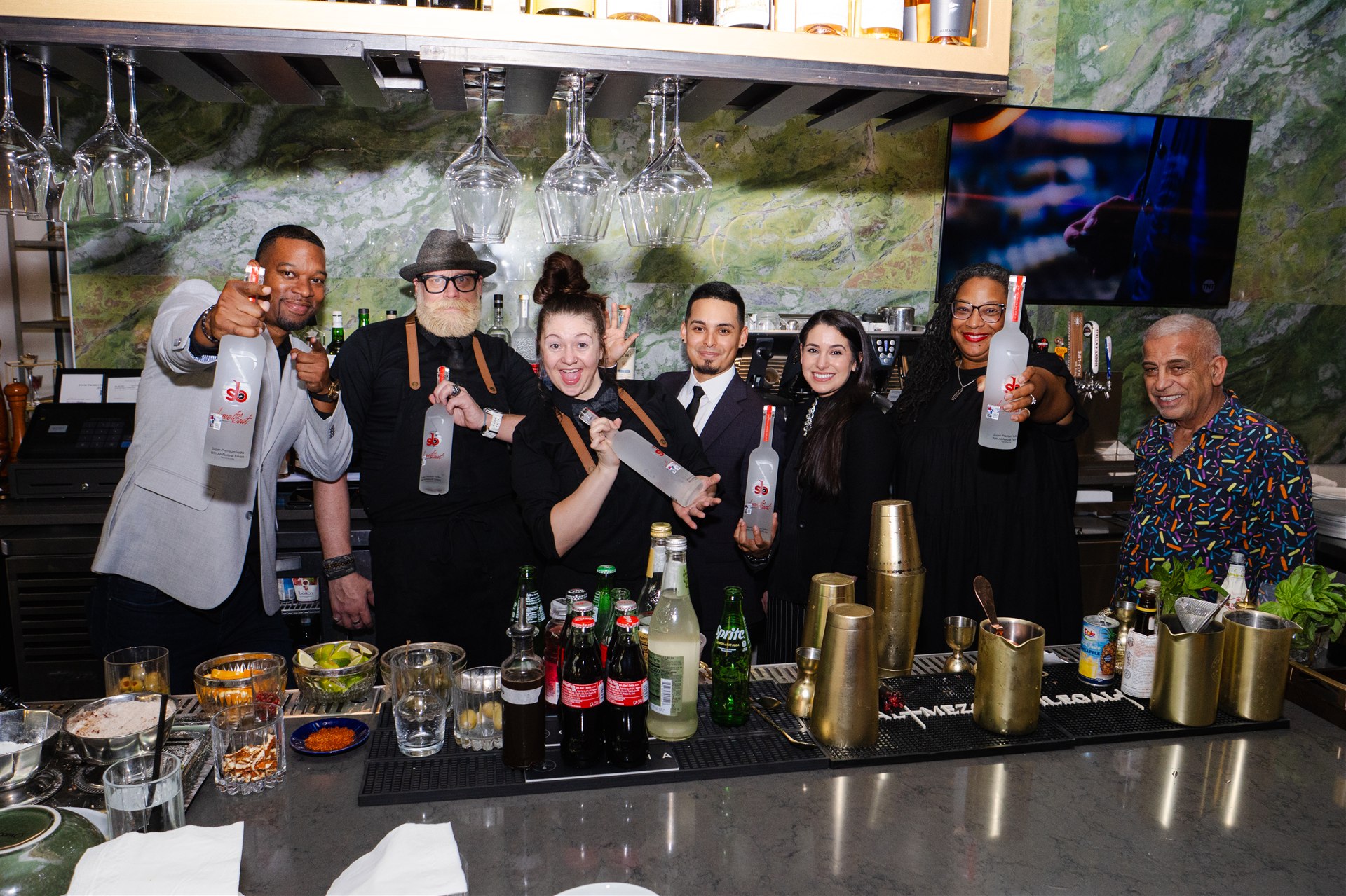 SweetBeat hospitality team celebrating together behind a bar with SweetBeat bottles